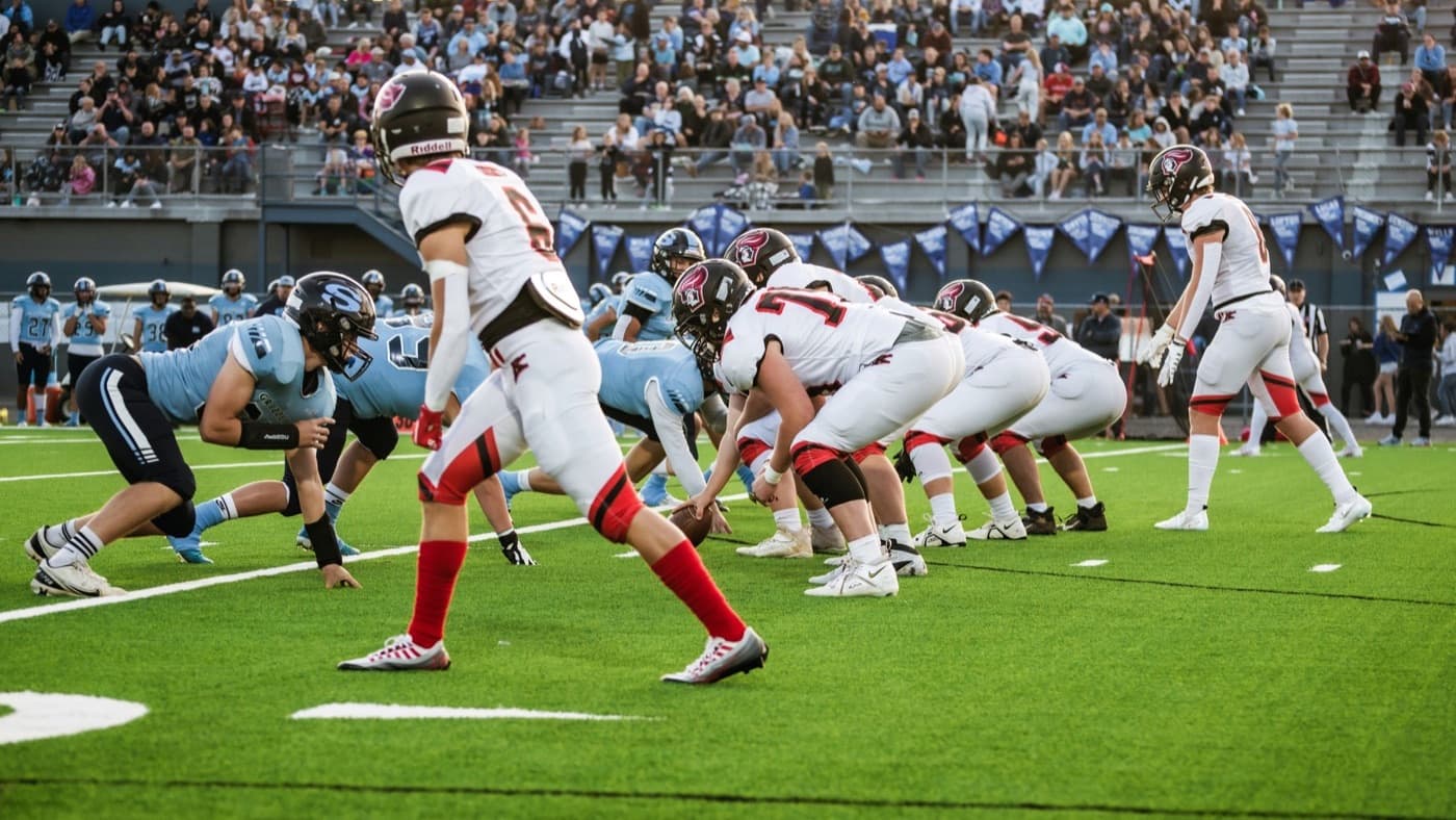 A high school football game in progress with spectators filling the stands