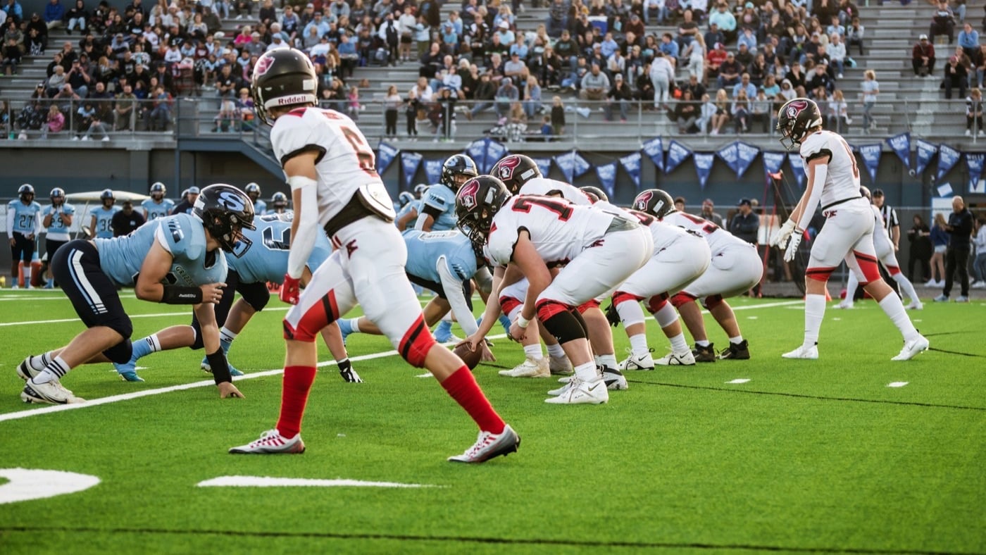 A high school football game in progress with spectators filling the stands
