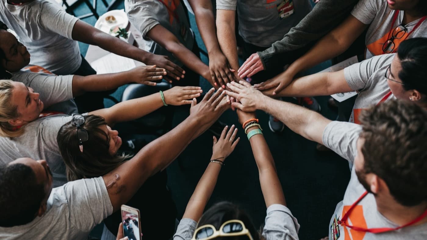 Volunteers putting their hands together in a circle before an event