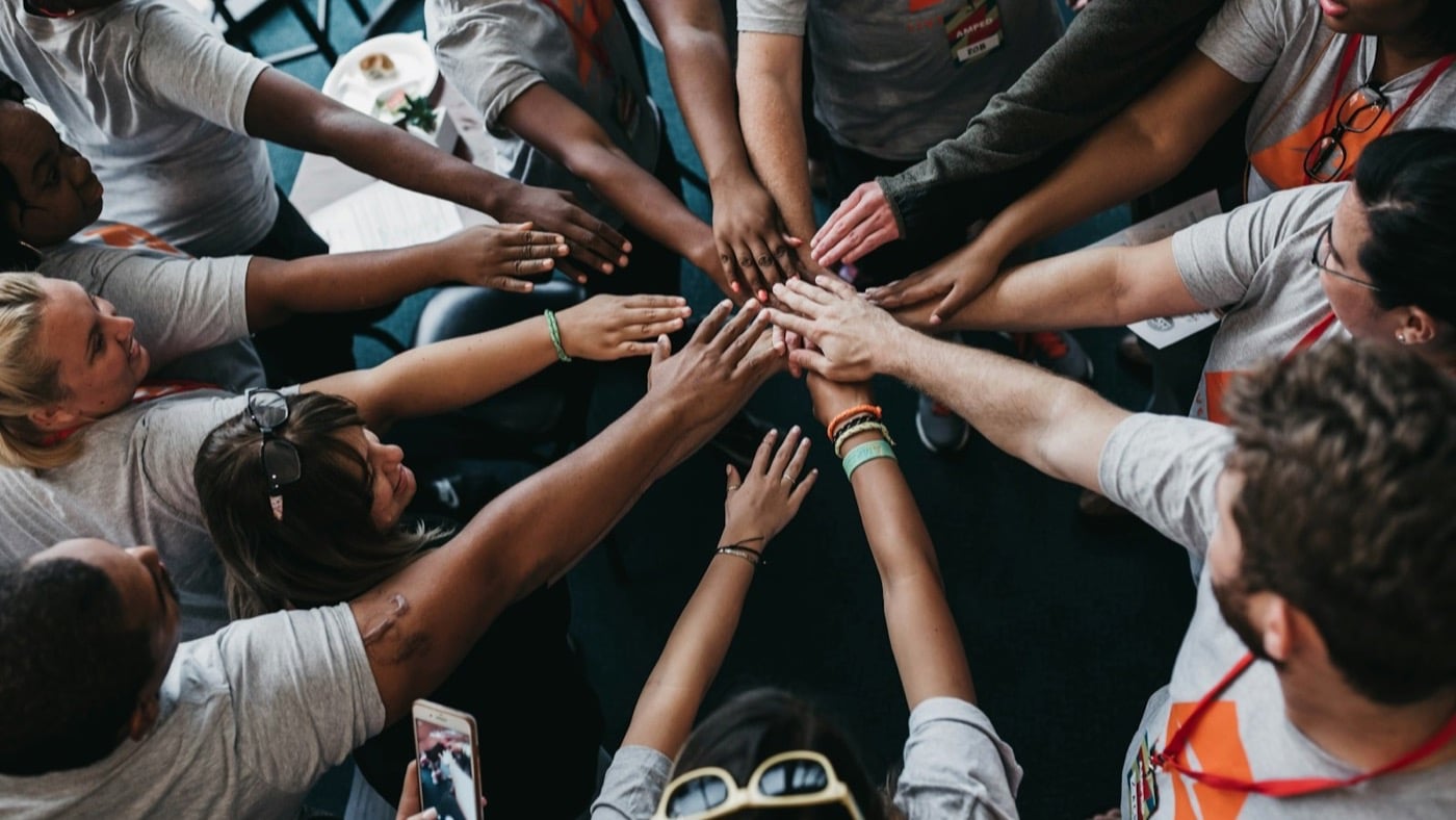 Volunteers putting their hands together in a circle before an event