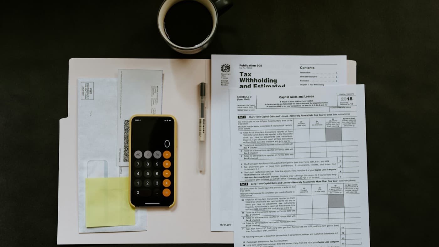 Tax forms, a calculator and a cup of coffee laid out on a desk