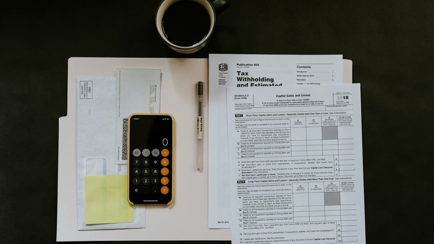 Tax forms, a calculator and a cup of coffee laid out on a desk