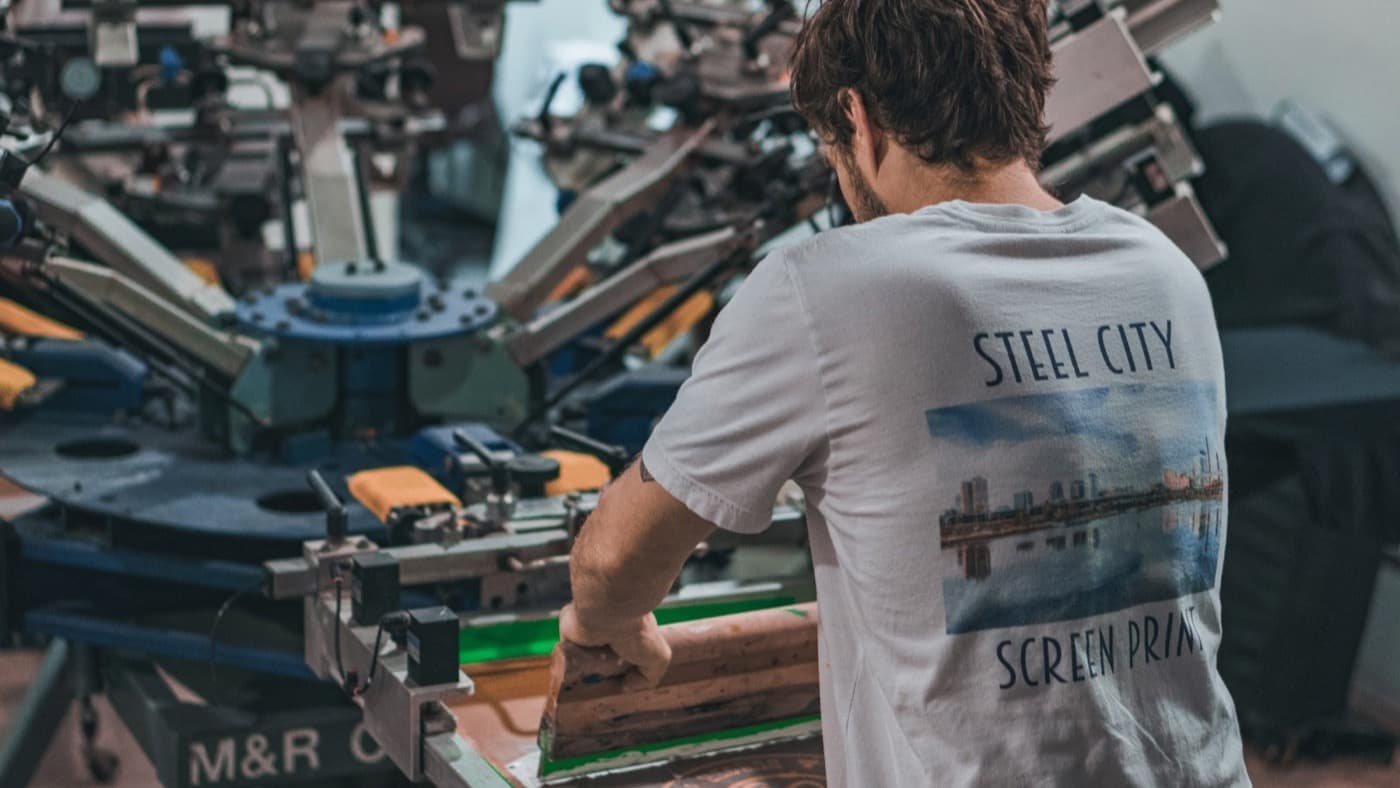 A screen printer working at a carousel press in an apparel workshop