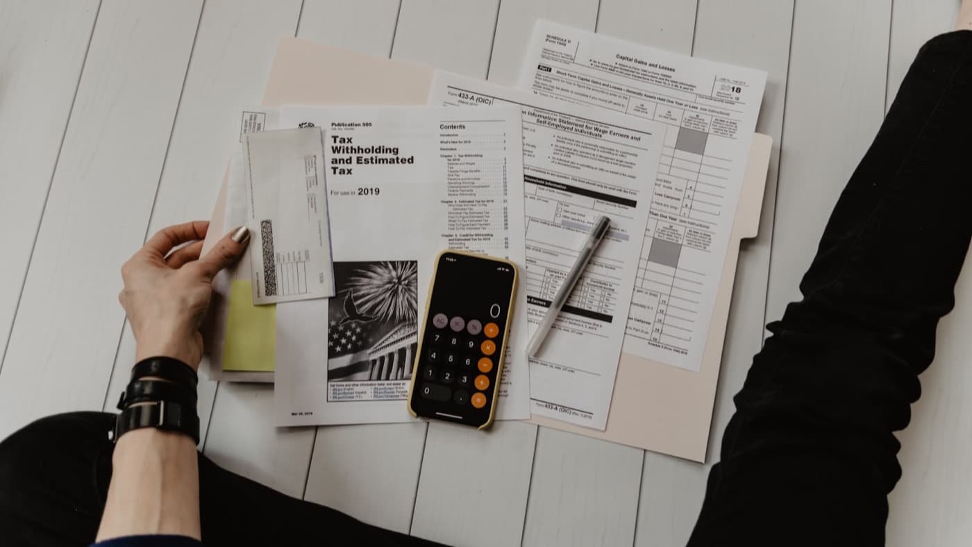 Tax paperwork, a calculator and a pen on a white desk