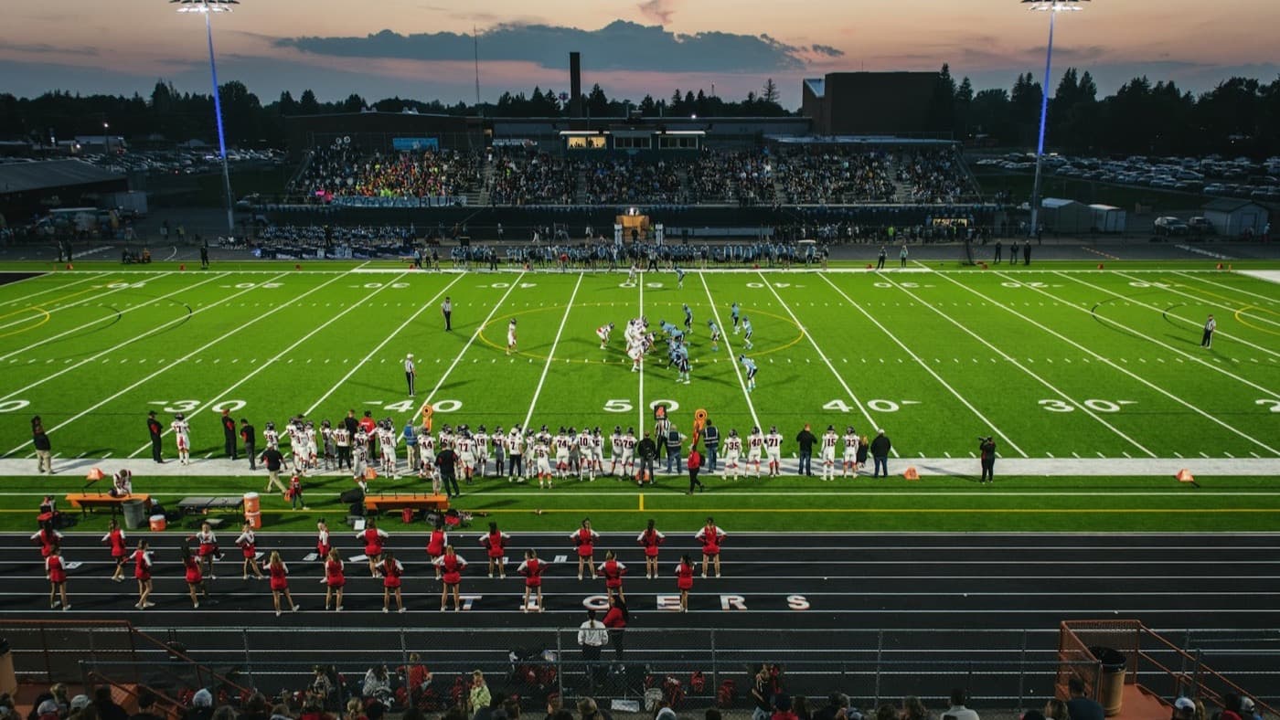 A high school football stadium at dusk with the crowd in the stands
